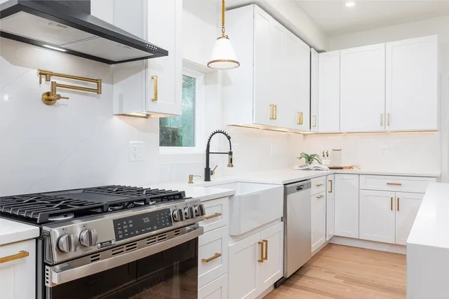 a white kitchen with sink stove and cabinets