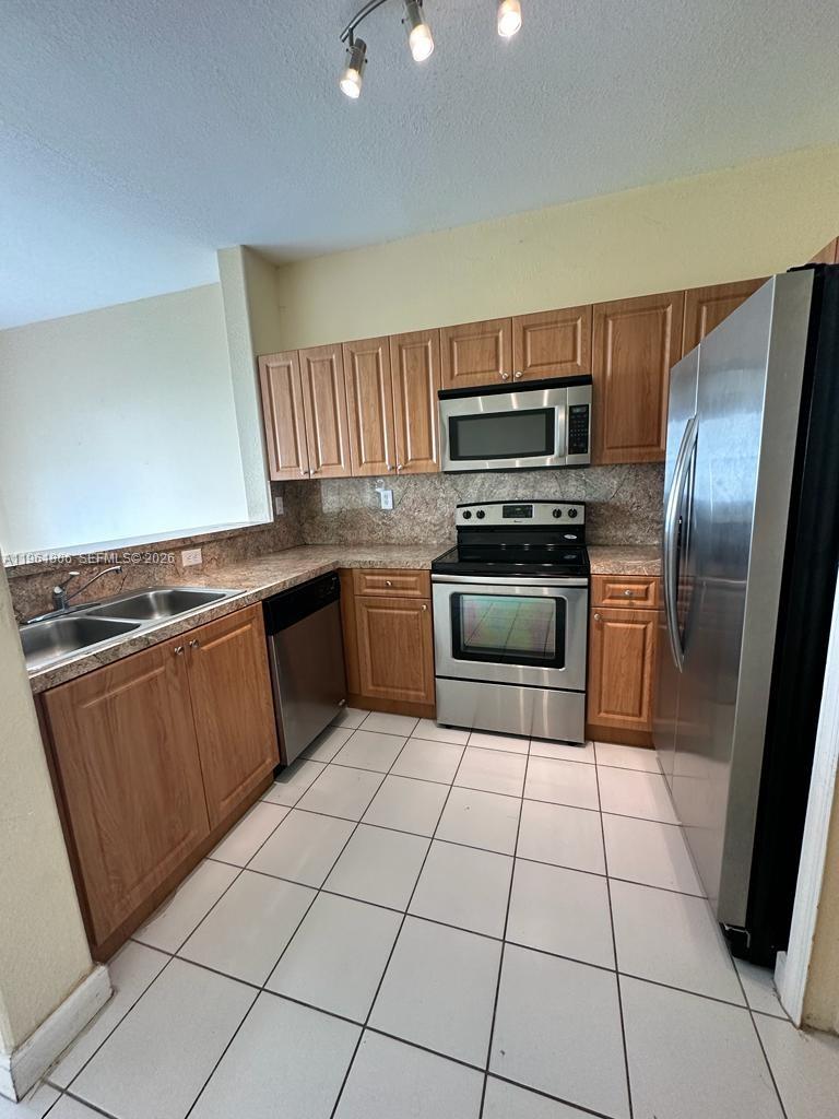 2900 Southeast 17th Avenue, Unit 103 Homestead, FL 33035 - Photo 6 of 16 a kitchen with granite countertop a stove top oven and stainless steel appliances