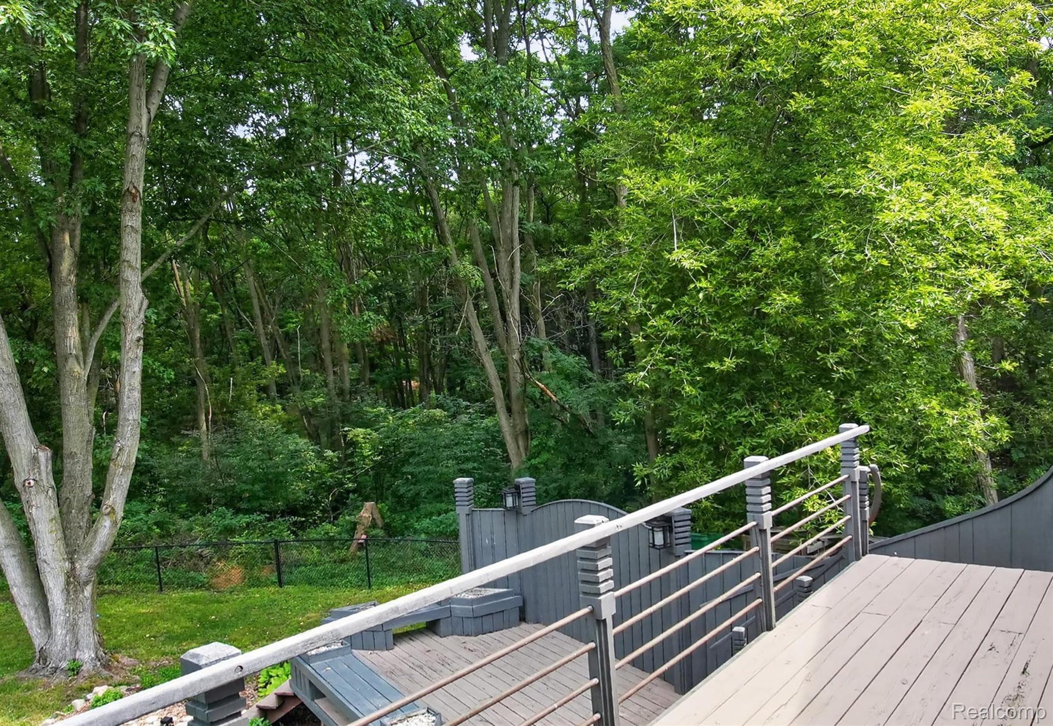 9319 Faussett Road Fenton, MI 48430 - Photo 49 of 70 Elevated wood-finish decking with contemporary horizontal railings, built-in seating, and lush surrounding trees