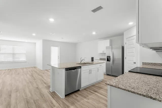 a kitchen with granite countertop stainless steel appliances a sink stove and cabinets