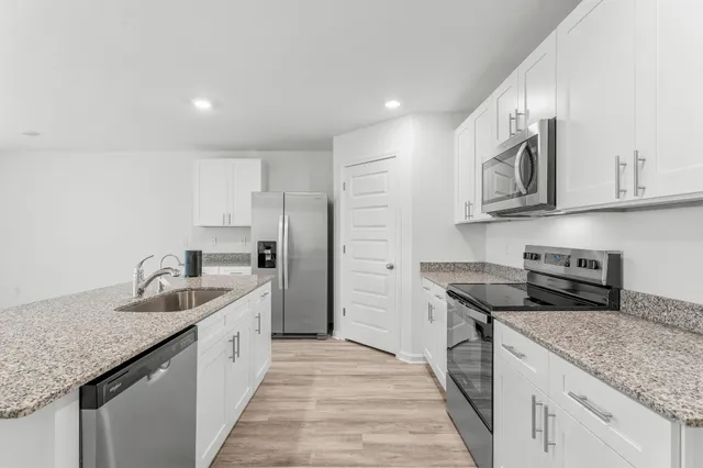 a kitchen with a sink a stove a refrigerator and white cabinets