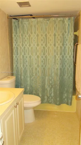 a bathroom with a sink a toilet and shower curtain