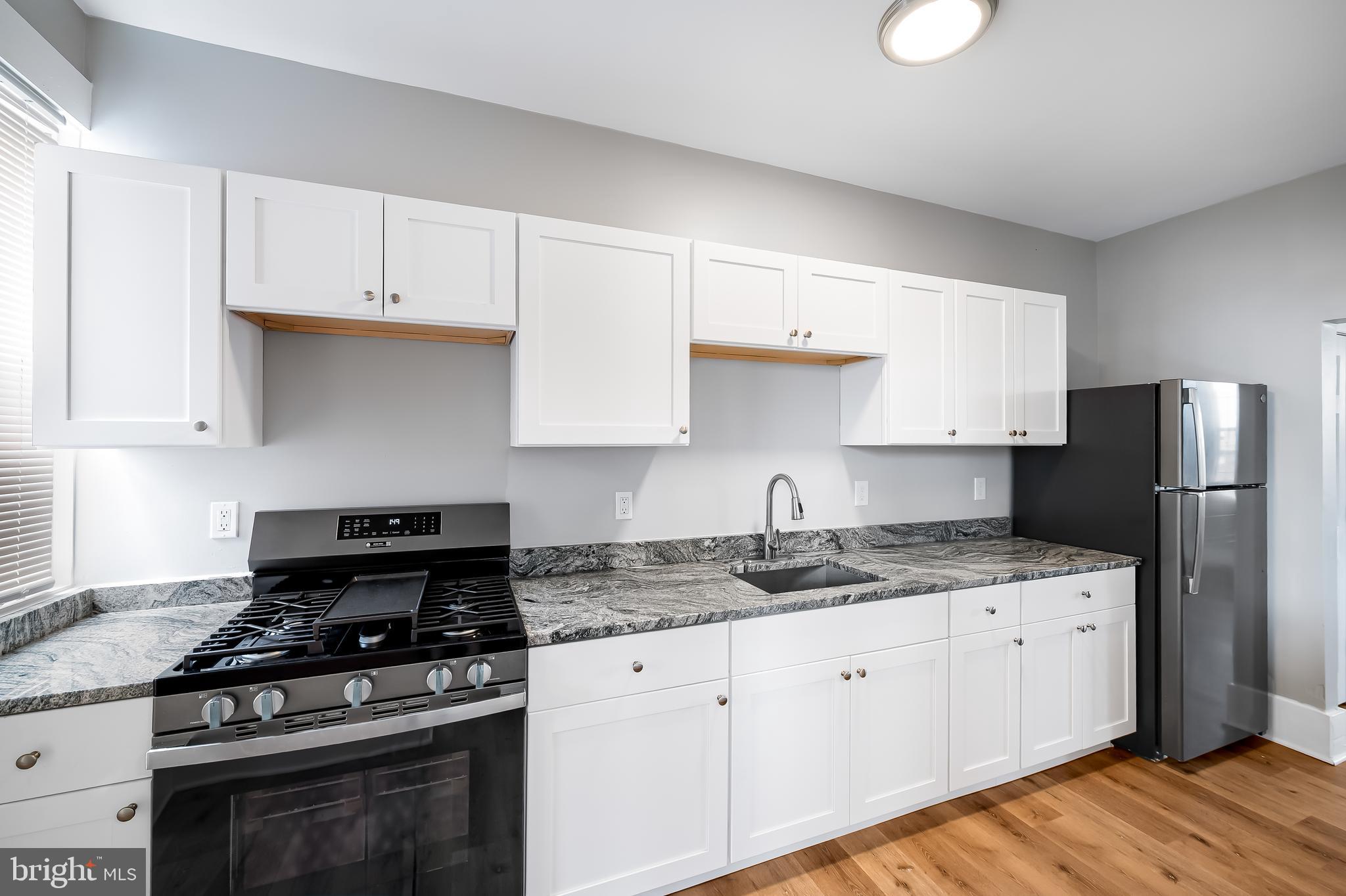 3003 Kentucky Avenue Baltimore, MD 21213 - Photo 13 of 32 a kitchen with granite countertop a stove sink and cabinets