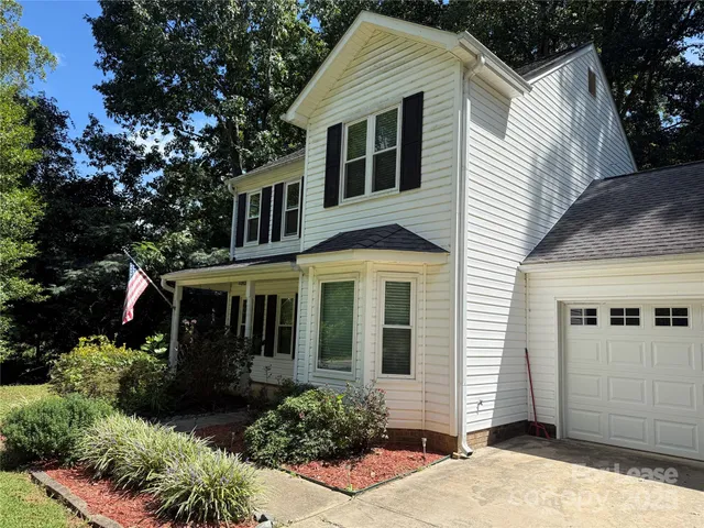 a view of a white house with large windows and potted plants