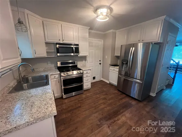 a kitchen with granite countertop a refrigerator stove and sink