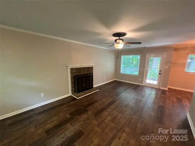 an empty room with wooden floor fireplace and windows