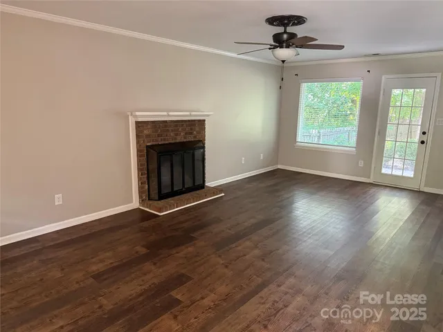 an empty room with wooden floor chandelier and windows
