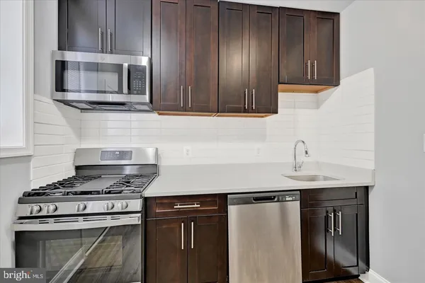 a kitchen with stainless steel appliances granite countertop a stove microwave and sink