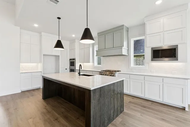 a kitchen with stainless steel appliances kitchen island granite countertop a stove and a sink