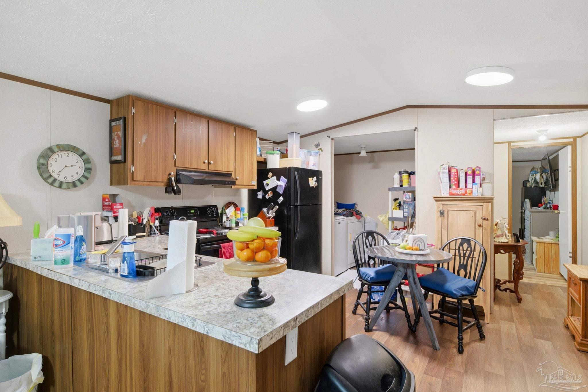 3338 Bob Tolbert Road Navarre, FL 32566 - Photo 8 of 29 a kitchen with stainless steel appliances granite countertop a refrigerator a sink dishwasher a dining table and chairs with wooden floor