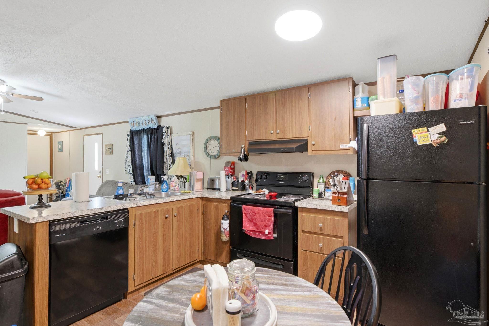 3338 Bob Tolbert Road Navarre, FL 32566 - Photo 9 of 29 a kitchen with stainless steel appliances granite countertop a refrigerator a sink dishwasher a stove a dining table and chairs with wooden floor