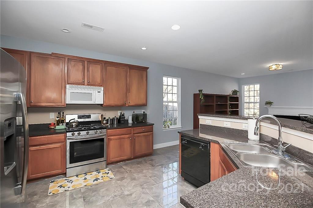 7769 East Berkeley Road Denver, NC 28037 - Photo 13 of 31 a kitchen with stainless steel appliances granite countertop wooden cabinets a stove top oven a sink and dishwasher