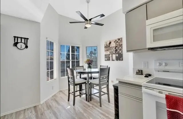 a kitchen with stainless steel appliances granite countertop a dining table chairs a sink and cabinets