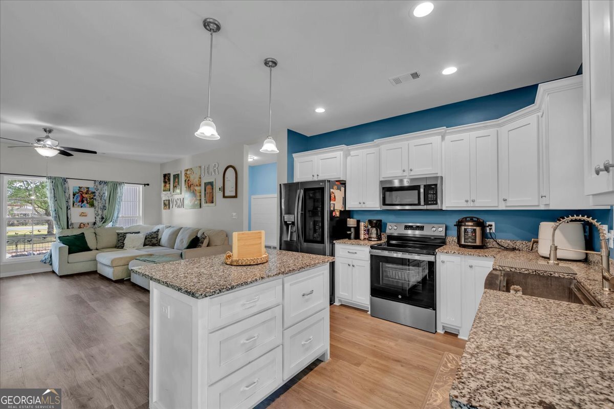 144 Summit Drive Byron, GA 31008 - Photo 11 of 42 a kitchen with granite countertop kitchen island stainless steel appliances a stove a sink a refrigerator a stove a dining table and chairs