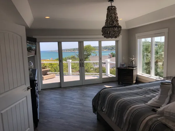 a bedroom with a bed a large window and wooden floor