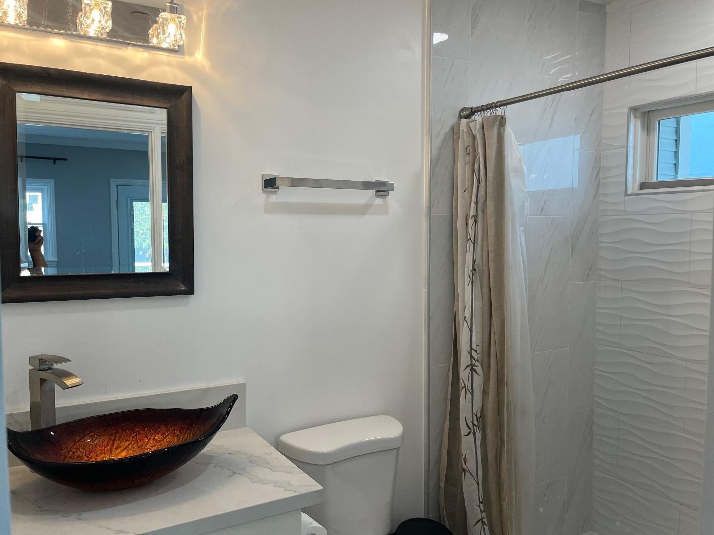 1073 Eighth Street Monterey, CA 93940 - Photo 8 of 11 a bathroom with a sink a toilet and a mirror