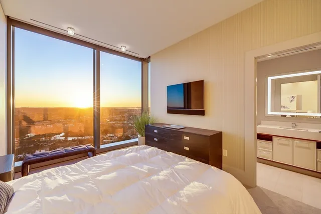 a spacious bedroom with a large bed and a flat tv screen next to a window