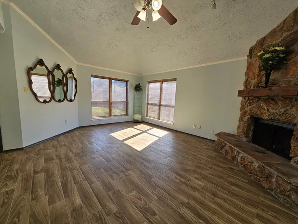 an empty room with wooden floor fireplace and window