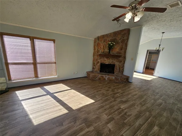 a view of an empty room with wooden floor fireplace and a window