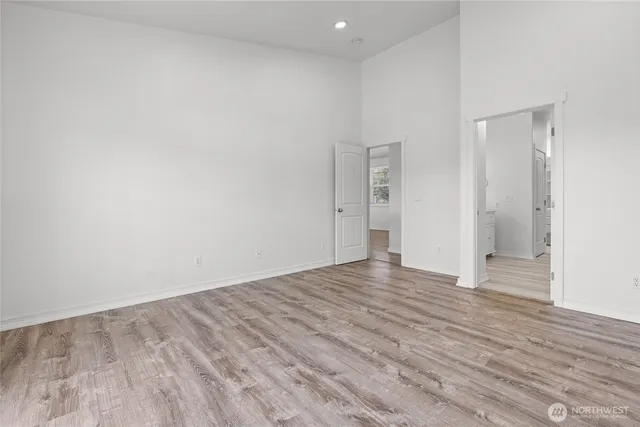 a view of an empty room with wooden floor and closet