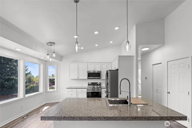 a kitchen with kitchen island granite countertop a stove a sink and a refrigerator with wooden floor