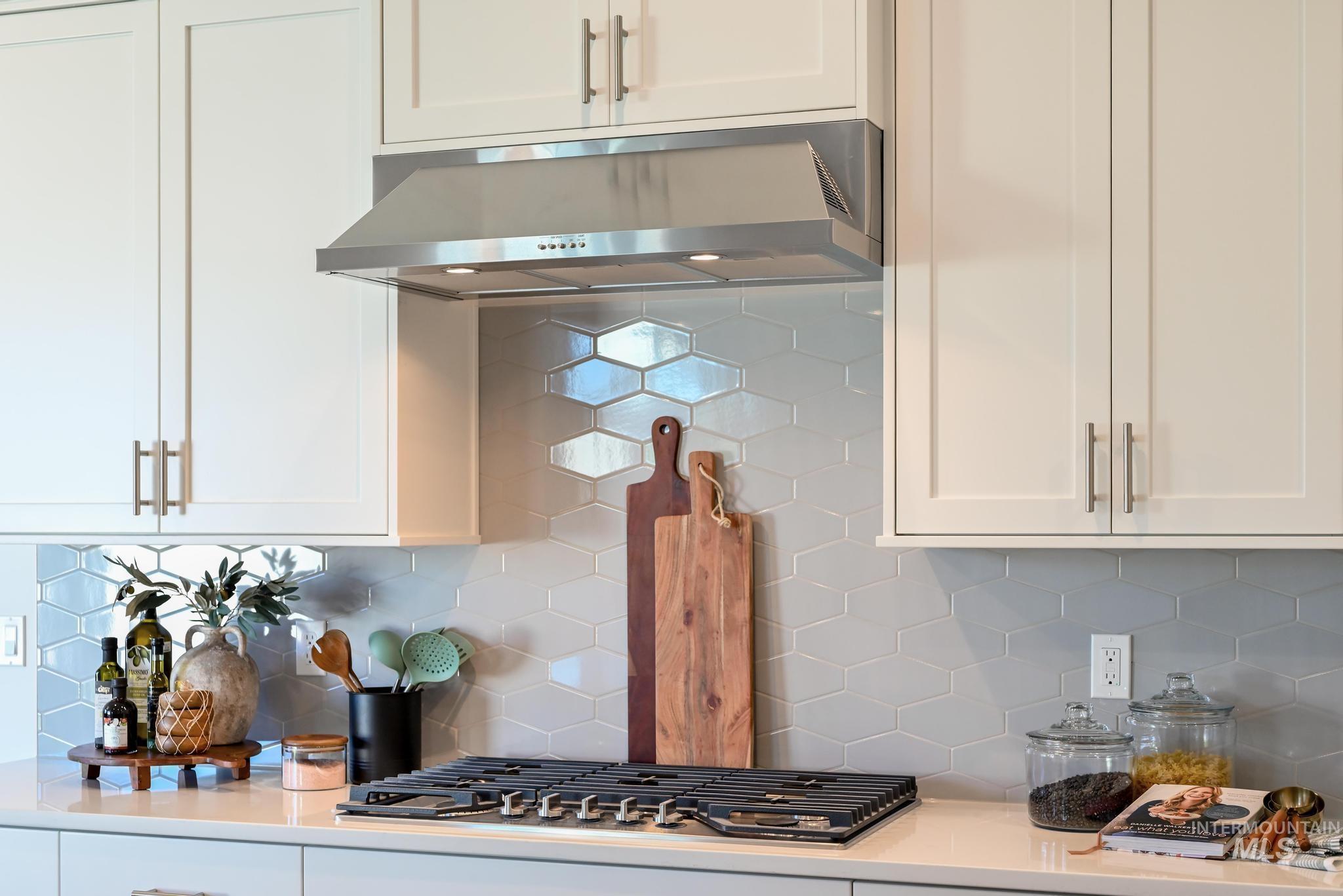 9074 West Moonglade Street Star, ID 83669 - Photo 12 of 40 Kitchen featuring white cabinetry, stainless steel range hood, built-in gas cooktop, light-toned countertop, and hexagonal tile backsplash