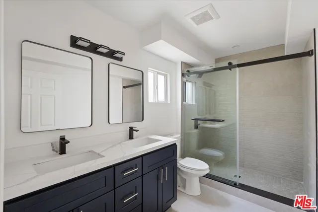 a bathroom with a granite countertop sink toilet a mirror and shower