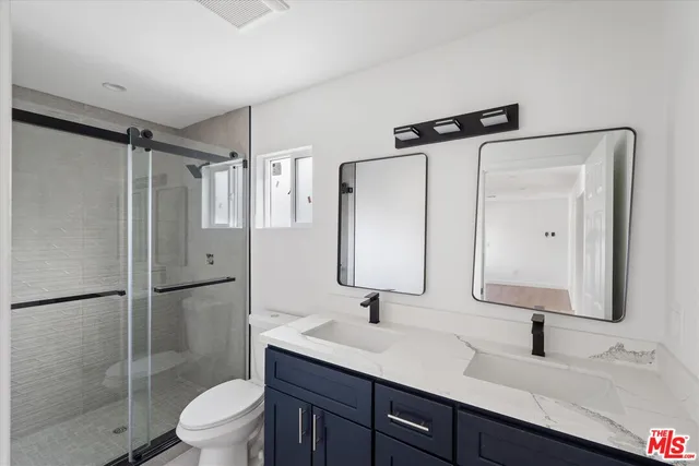a bathroom with a sink toilet double vanity and shower