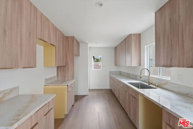 a kitchen with a sink a stove cabinets and wooden floor