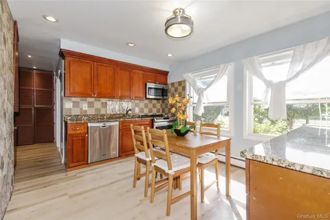 a kitchen with stainless steel appliances granite countertop table chairs and large window