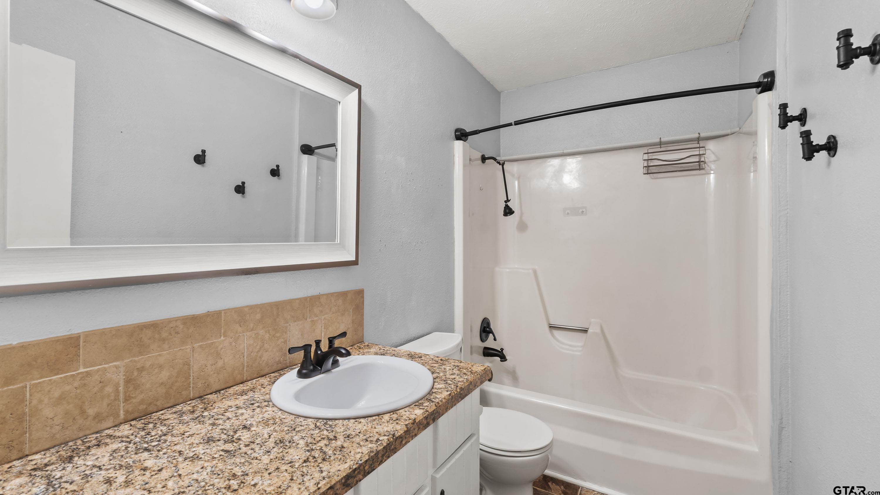 3418 Main Street Texarkana, TX 75503 - Photo 22 of 28 a bathroom with a granite countertop sink and a mirror
