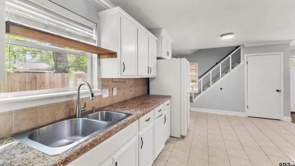 a kitchen with a sink a counter top space cabinets and a window