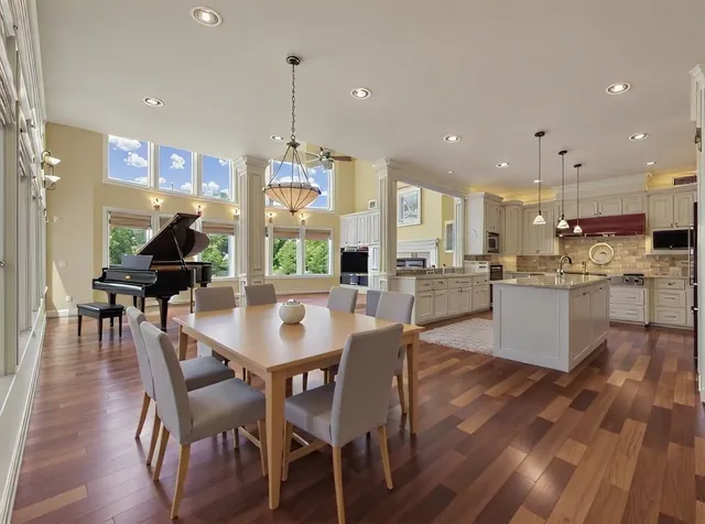 a view of a dining room and livingroom with furniture wooden floor a rug a fireplace
