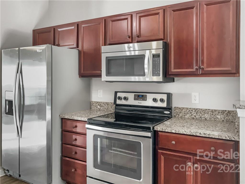 6156 Prosperity Church Road Charlotte, NC 28269 - Photo 17 of 31 a kitchen with granite countertop stainless steel appliances and wooden cabinets