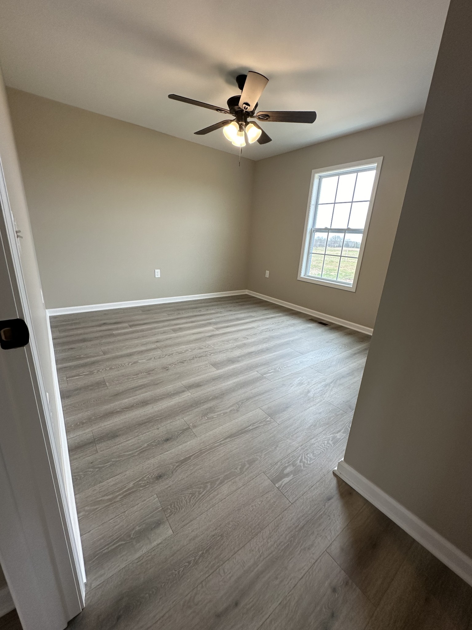185 Rigling Road Loretto, TN 38469 - Photo 17 of 24 an empty room with wooden floor fan and windows