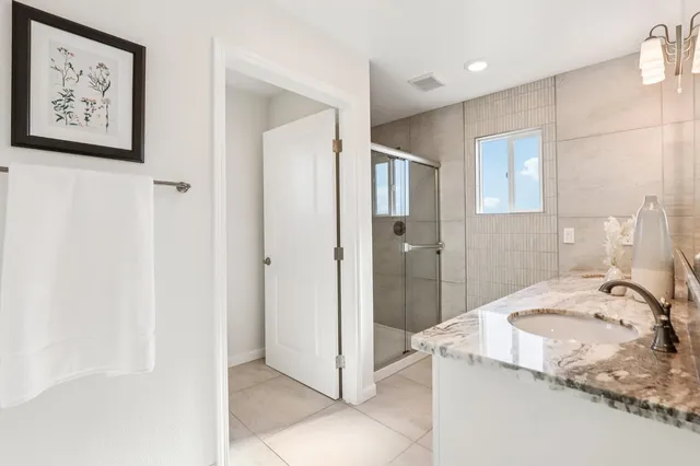 a bathroom with a granite countertop sink and a shower