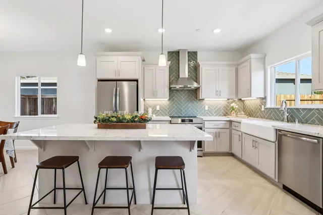 a kitchen with stainless steel appliances kitchen island a table chairs sink and cabinets
