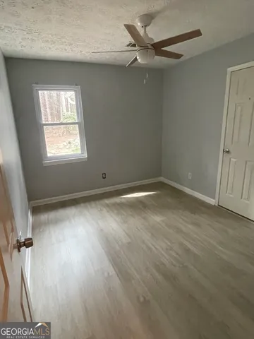 an empty room with wooden floor fan and windows