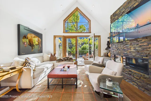 a living room with furniture a fireplace and a floor to ceiling window
