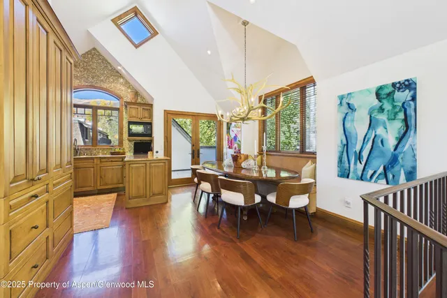 a dining room with wooden floor a chandelier a wooden table and chairs