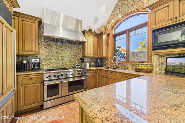 a kitchen with stainless steel appliances granite countertop a stove a sink and a microwave