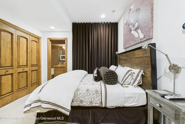 a bedroom with a bed and dresser with wooden floor