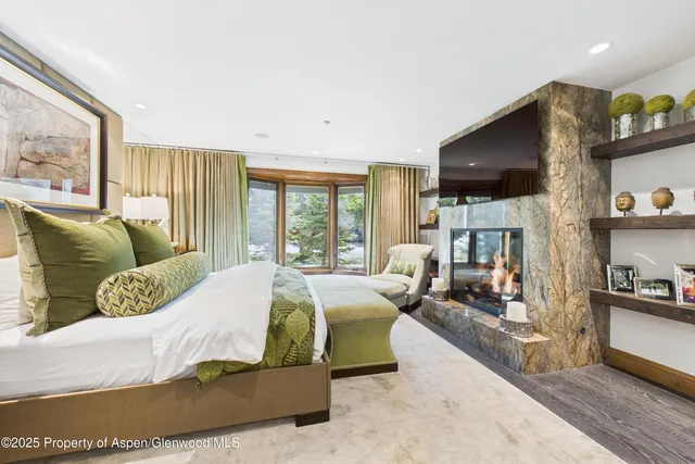 a bedroom with a bed a couch and large windows