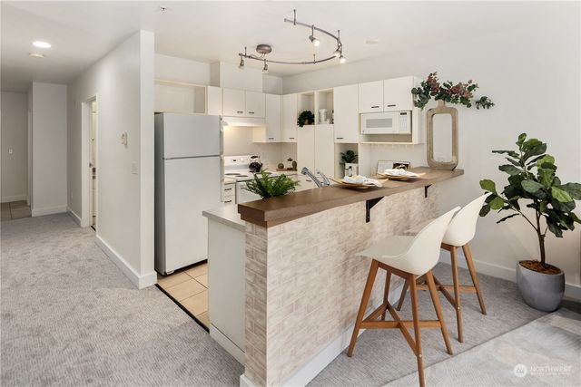 a very nice looking dining room with kitchen island granite countertop furniture a refrigerator and a chandelier