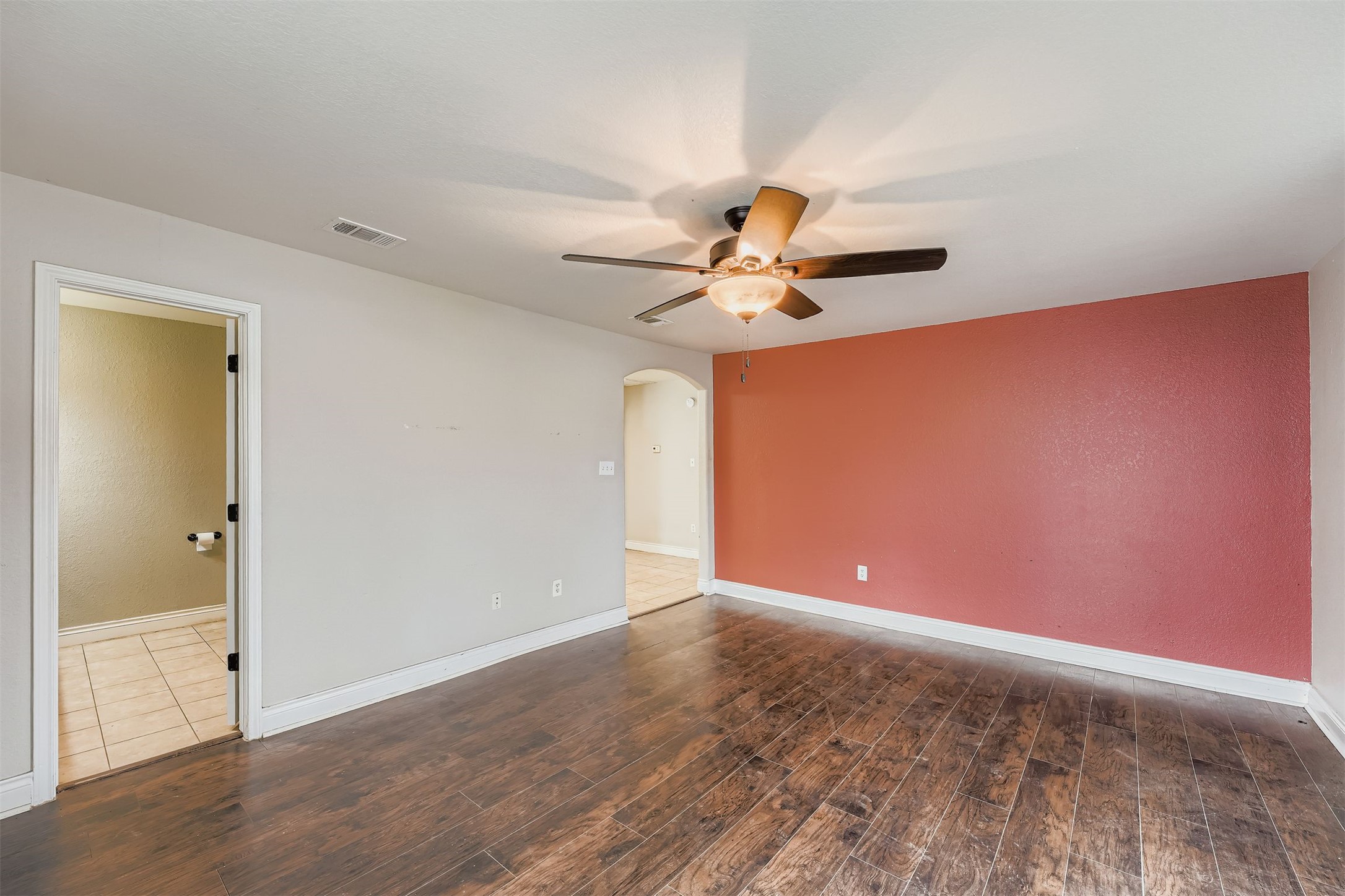 304 South Main Street Elgin, TX 78621 - Photo 10 of 25 Unfurnished room featuring arched walkways, dark wood finished floors, and ceiling fan