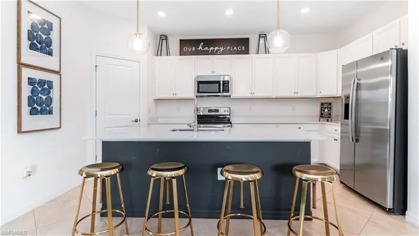 a kitchen with stainless steel appliances a table chairs refrigerator and sink