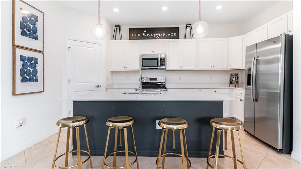 a kitchen with stainless steel appliances a table chairs refrigerator and sink