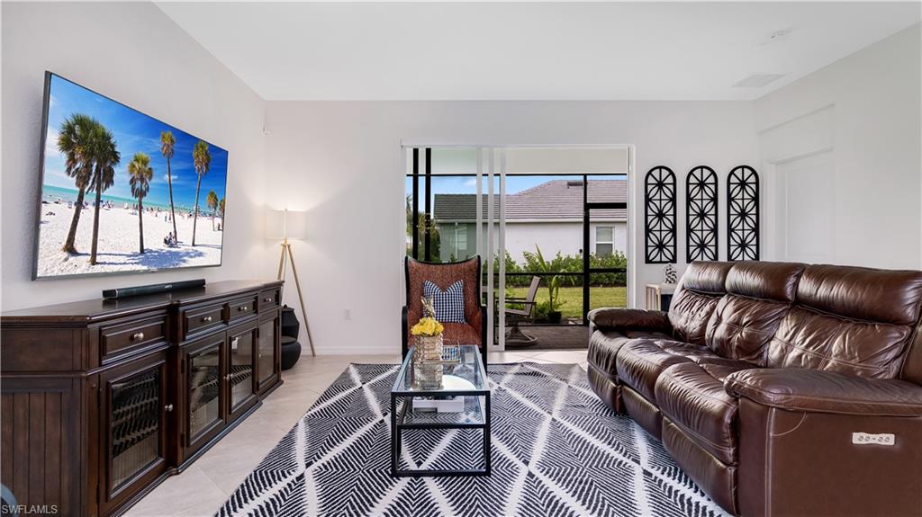 2425 Orchard Street Naples, FL 34120 - Photo 8 of 28 a living room with furniture a flat screen tv and a floor to ceiling window