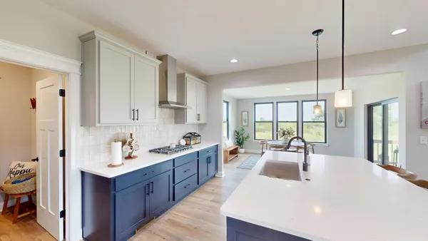 a large kitchen with kitchen island a large window a sink a counter space and a view of living room
