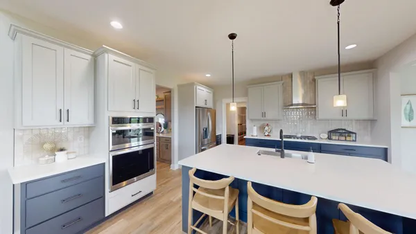 a kitchen with stainless steel appliances a stove a sink a refrigerator a center island and a wooden floor